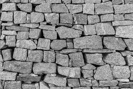 旧石砖墙的单色背景岩石建筑圆形黑色材料白色建筑学灰色卵石花岗岩图片
