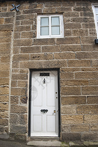 一个村庄中的老英语乡村小屋住宅农村房子石头入口窗户历史性白色建筑学木头图片