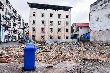 有旧建筑背景的蓝色废件回收桶垃圾箱水泥岩石塑料石头地面街道环境垃圾垃圾桶图片