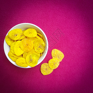 香蕉薯片保存在碗中 粉红色背景的美容薄荷热带香蕉早餐果汁黄色筹码桌子甜点食物图片