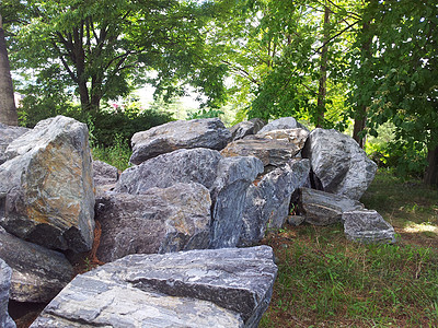 在公共公园绿树之间定居的大块石头或大块石头侵蚀遗产森林环境旅行沉积材料麻面悬崖公园图片