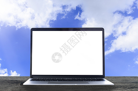 木制桌子和蓝天背面有白色空白屏幕的笔记本电脑图片