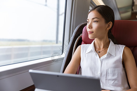 在火车上使用笔记本电脑旅行的亚洲妇女 商业妇女通过计算机工作 在往返上班时向窗外看望着窗口图片