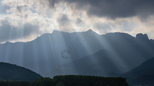 明亮的阳光在云洞中闪耀到西班牙山脉的黑暗景象图片