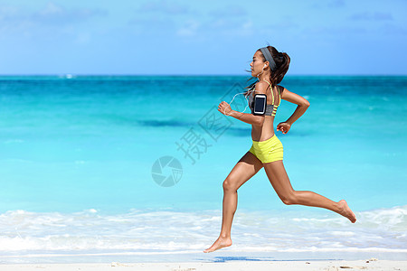 女性在海滩上用电话运动臂盘听音乐的赛跑者图片