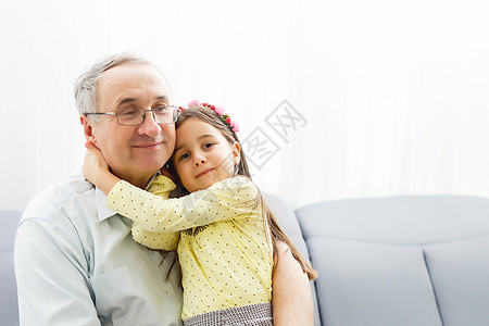 外孙抱祖父的有趣的生活方式肖像画退休房间微笑女孩男性技术老年孩子沙发祖父母图片