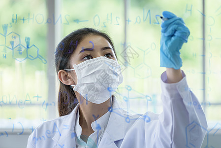 亚洲年轻女学生科学家有写作和研究i管子蓝色器皿烧瓶化学品女性眼镜生物女孩学习图片