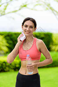 美丽的女子跑步者已经疲惫不堪 为饮用水和饮水而休息瓶子花园女士公园赛跑者出汗有氧运动训练疲劳女性图片