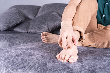 年轻人在家坐在沙发上时抓着脚 在医疗或日常生活概念上接受治疗和治疗疾病湿疹疼痛过敏刺激脚趾皮疹感染男性划痕图片
