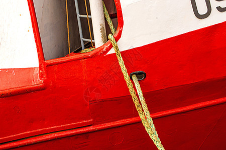 拖网渔船在红船体上航海晴天栏杆白色船运红色港口安全海洋麻绳图片