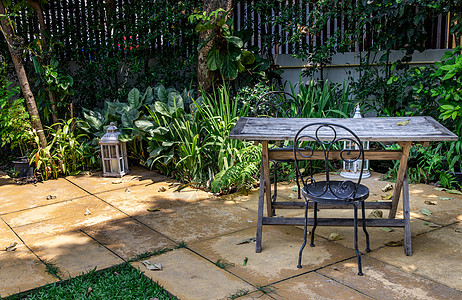 花园餐厅旧木制桌和室外花园的黑钢椅背景