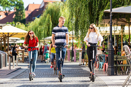 时髦时髦的一群朋友在城市环境中骑着公共租赁电动滑板车 斯洛文尼亚卢布尔雅那新型环保现代公共城市交通闲暇生态力量摩托车男人电池活动图片