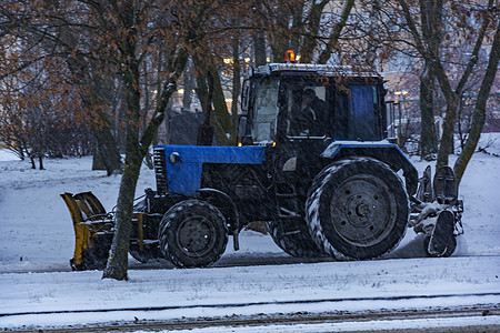 拖拉机Balorus在下雪时清理人行道上的雪背景图片