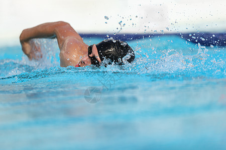 游泳池运动员在室内训练以进行专业比赛 游泳运动员在体育场游泳练习 手臂溅水爬行 蓝色水背景上的复制空间背景图片