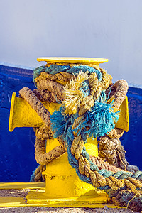 带锚系线的柱状体晴天圆圈海洋航海绳索黄色阴影码头船运港口图片