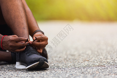 坐在鞋带上尝试跑鞋的黑人男子运动鞋训练慢跑者运动员健身房跑步衬衫男性活动男人图片