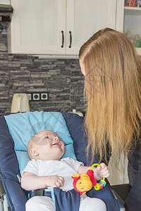母性概念 婴儿对母亲微笑女士快乐孩子厨房座椅玩具说谎男生儿子房间图片