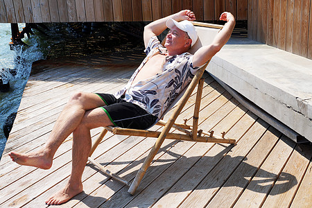 坐在阳台上的遮太阳护晒员上财富活动退休露台海洋微笑休闲衬衫休息成功图片