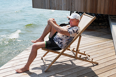 坐在阳台上的遮太阳护晒员上休息主义活动甲板白发温泉中年人繁荣成功海景图片