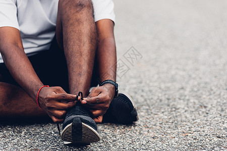 坐在鞋带上尝试跑鞋的黑人男子衬衫健身房男人跑步体育场慢跑者活动运动训练赛跑者图片