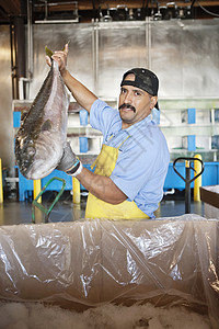 持有鲑鱼的成熟捕捞者肖像商业渔业胡子批发市场工业成人围裙男人店铺市场图片