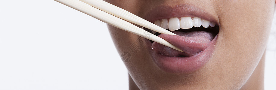 玩耍的年轻女人 用筷子在白种背景下伸出舌头鬼脸特写牙齿成人视图成年人成年种族女性恶作剧图片