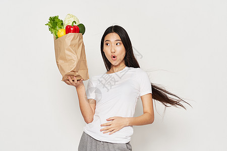一个身材苗瘦的漂亮女孩 拿着一包蔬菜在吃图片