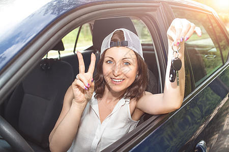 戴着帽子的漂亮女人 拿着新买车钥匙 在夏日对着镜头微笑图片