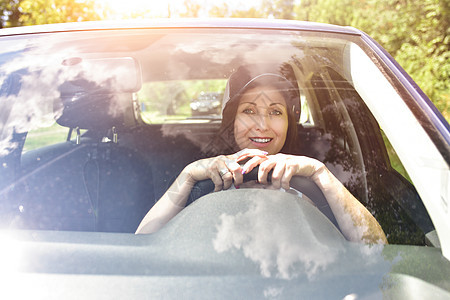 穿着帽子的美丽成年快乐女士 在夏日驾驶她的车喜悦女孩汽车商业窗户幸福快乐微笑乘客司机图片