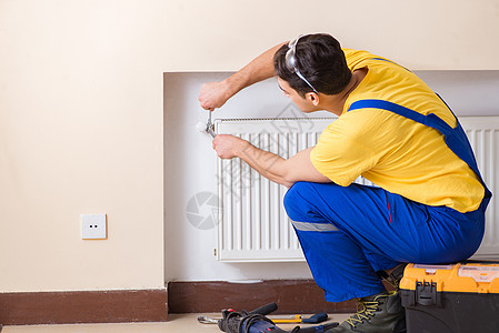 修理暖气板的年轻修理工承包商空调加热器温度机械散热器房子扳手服务活力男人图片