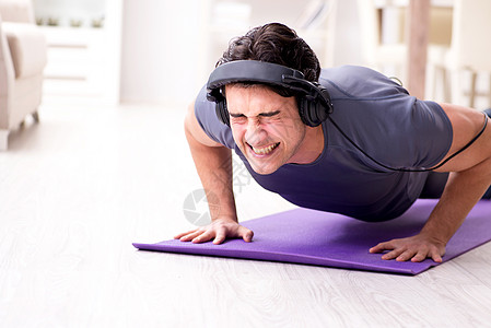 男人在家里做运动和听音乐耳机举重二头肌肌肉娱乐训练躯干俯卧撑享受有氧运动图片