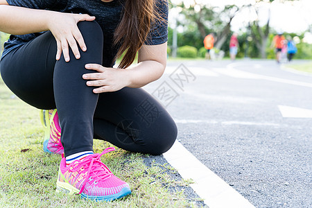 亚洲女性在公园的路上跑时用手握住膝盖受伤 因锻炼概念而受伤女士疼痛女孩运动跑步男人运动员训练赛跑者肌肉图片