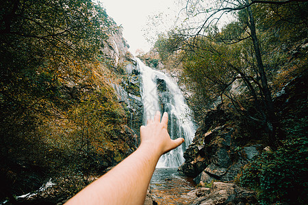 双向拍下一个失去焦点的手 到达巨大的瀑布蓝色国家苔藓风景溪流荒野公园寒意岩石叶子图片