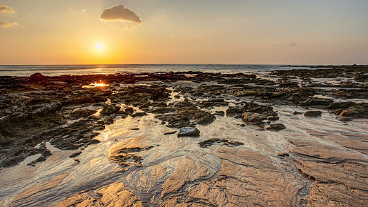 在低潮下显示沙状的金色日落光下的海滩上阳光波纹情调岩石支撑金子反射地平线海岸线天空图片