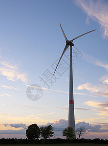 风力涡轮机和树木在多彩的日落下形成圆光影地标螺旋桨蓝色环境生产涡轮风车力量日出风景图片