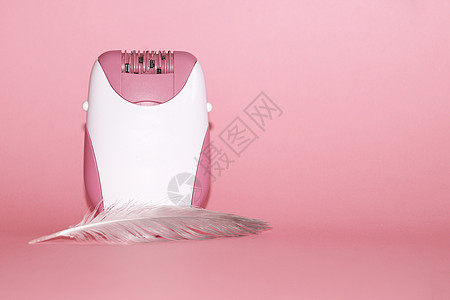 粉红色背景上的电动手控触角器和羽毛身体柔软度工具玫瑰沙龙皮肤科皮肤塑料生活方式卫生图片