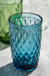靠近绿色和透明饮料杯的蓝玻璃几何像杯图片