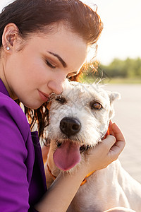 有魅力的年轻女子在公园里拥抱她的狗混种快乐日落微笑训练朋友伴侣犬类宠物动物图片