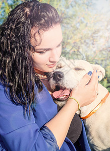 年轻女人在公园里拥抱她的狗混种幸福爪子伴侣日落朋友犬类女士友谊微笑图片