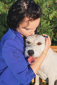 年轻女人在公园里拥抱她的狗宠物成人伴侣日落友谊动物混种女士快乐幸福图片