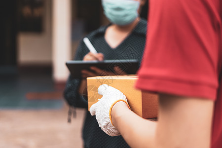 女性购物妇女在家门口收到快递寄来的包裹后在数字手机上签到 因此必须戴口罩以防止疾病传播 网购和快递 隔离流感包装船运命令商业男人签约女士背景