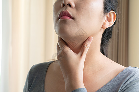 喉咙痛 美丽的女人手摸着她疼痛的脖子身体保健吞咽症状伤害成人病人流感甲状腺感染背景图片