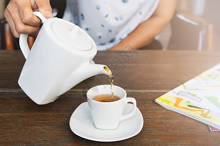木桌上泡茶的雌性风景桌子饮料咖啡店茶壶餐具飞碟液体杯子早餐时间图片