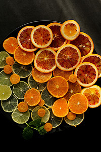 黑色圆盘上的新鲜柑橘水果 黑色底底的黑板上色彩饮食橙子柠檬高架维生素茶点食物图片