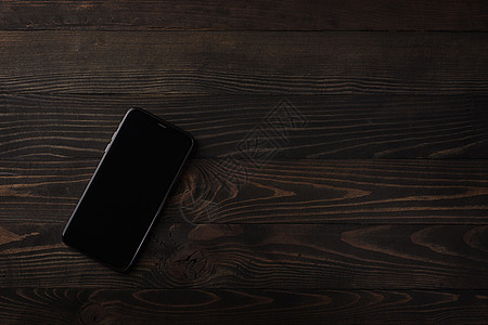 黑木桌背景上现代智能手机最接近的顶端视图图片