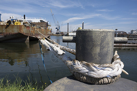 带船绳的系泊系船柱 码头上有系泊绳索的系船柱 停泊在港口码头的船只图片