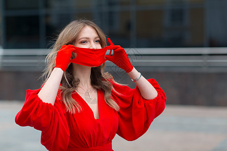 身着红色礼服和手套的年轻妇女戴上医疗防护面罩图片