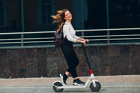 城市有电动摩托车的年轻女子女士活动自行车生态技术青年运动商务人士闲暇图片