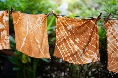 挂在户外花园的戴德巴迪克布工作动机遗产倾斜裙子染料衣服阳光材料织物背景图片