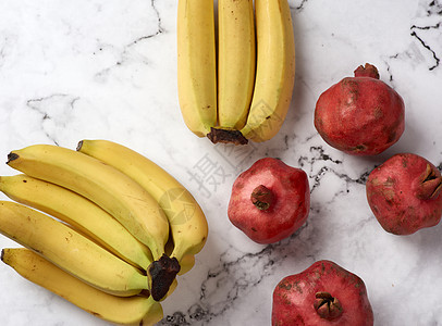 白大理石桌上成熟的红石榴和黄香蕉小吃饮食皮肤美食桌子工作室食物香蕉水果营养图片